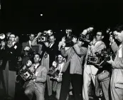 Black and white photograph of a group of photographers with their cameras at a premiere