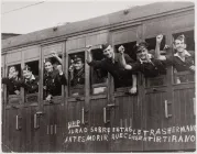 Young men in WWII waving their hands as they depart on a train. 