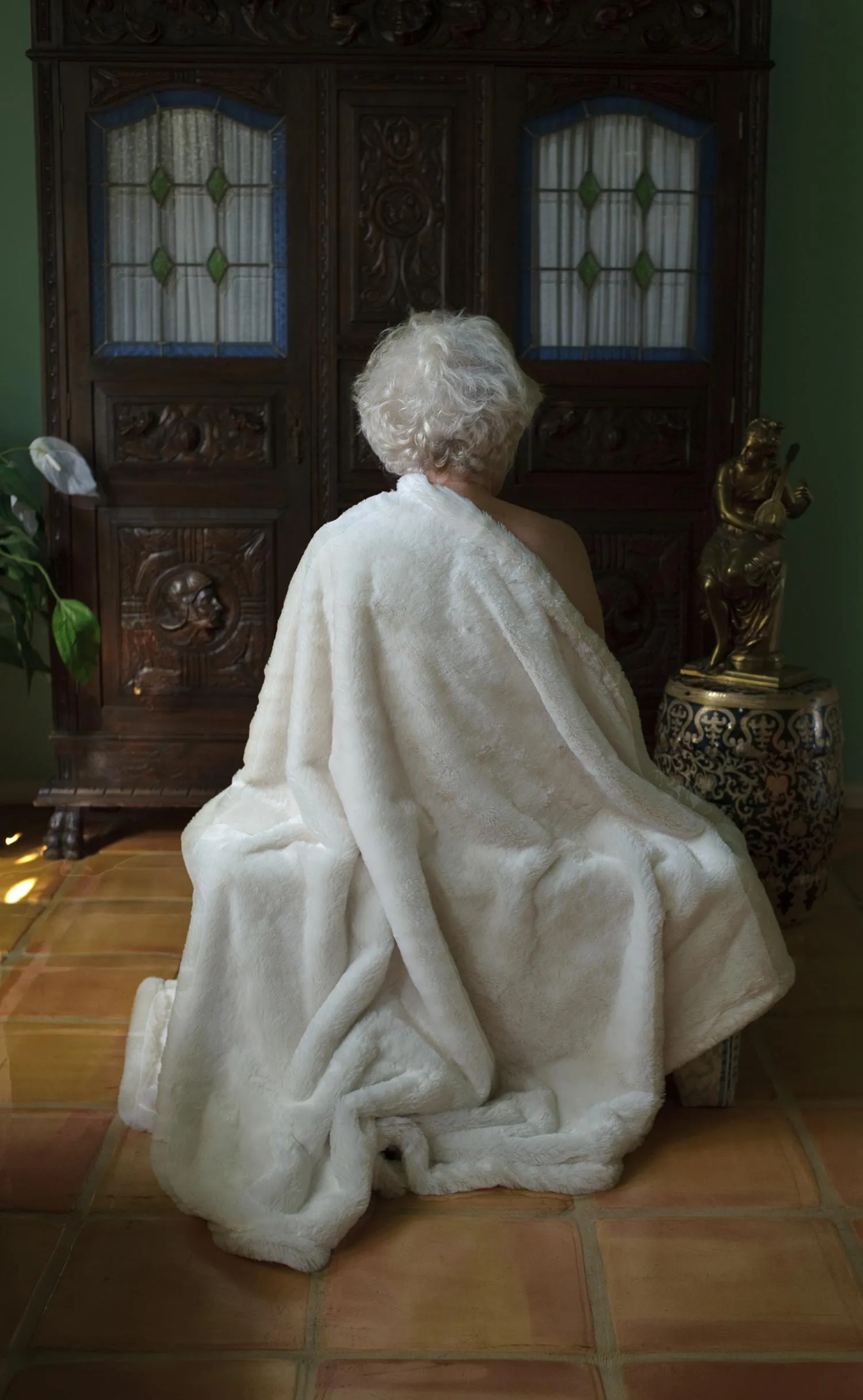 An elderly lady wrapped in a blanket.