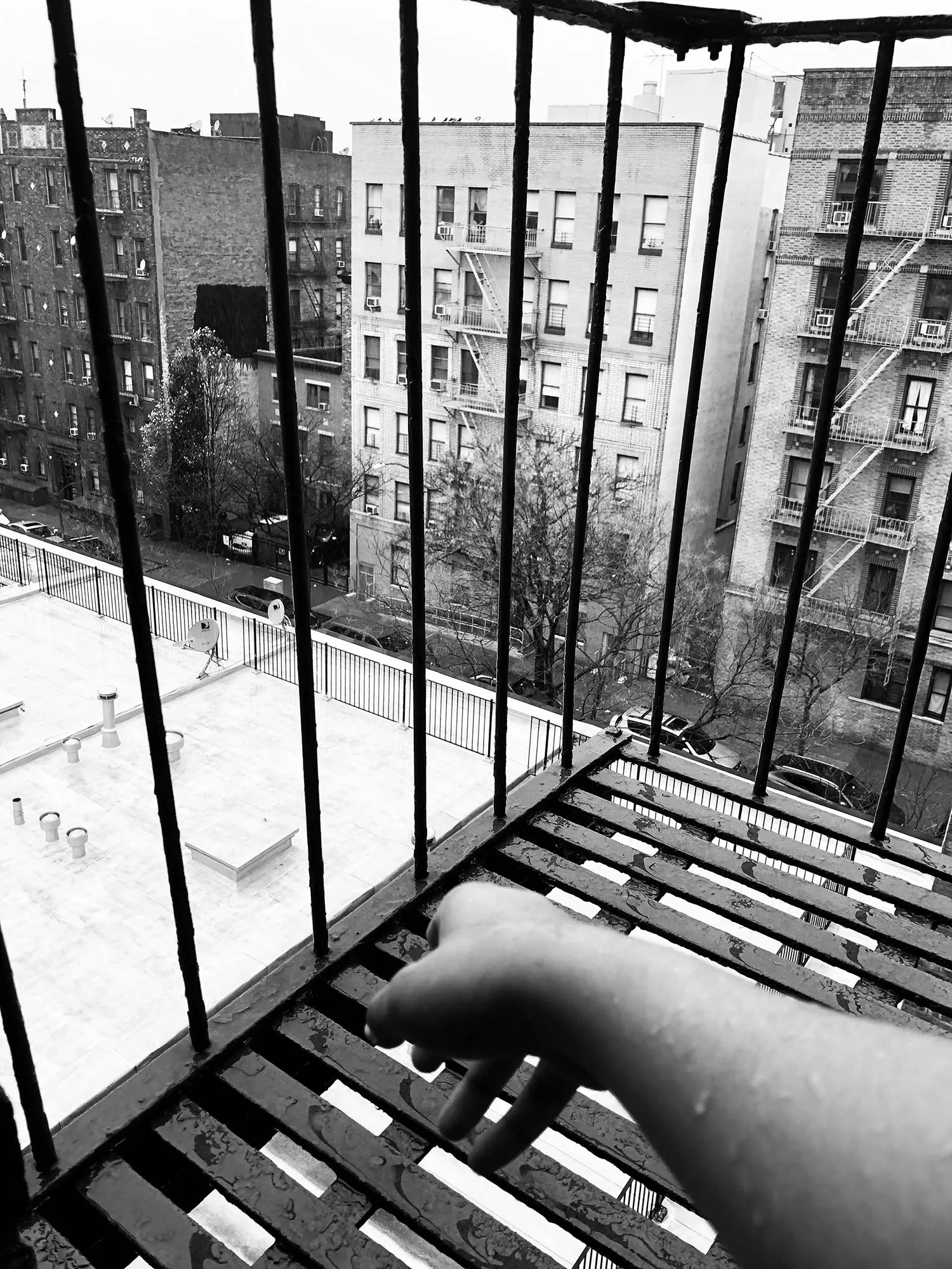 The hand of someone on their firescape, brownstones in the background. 