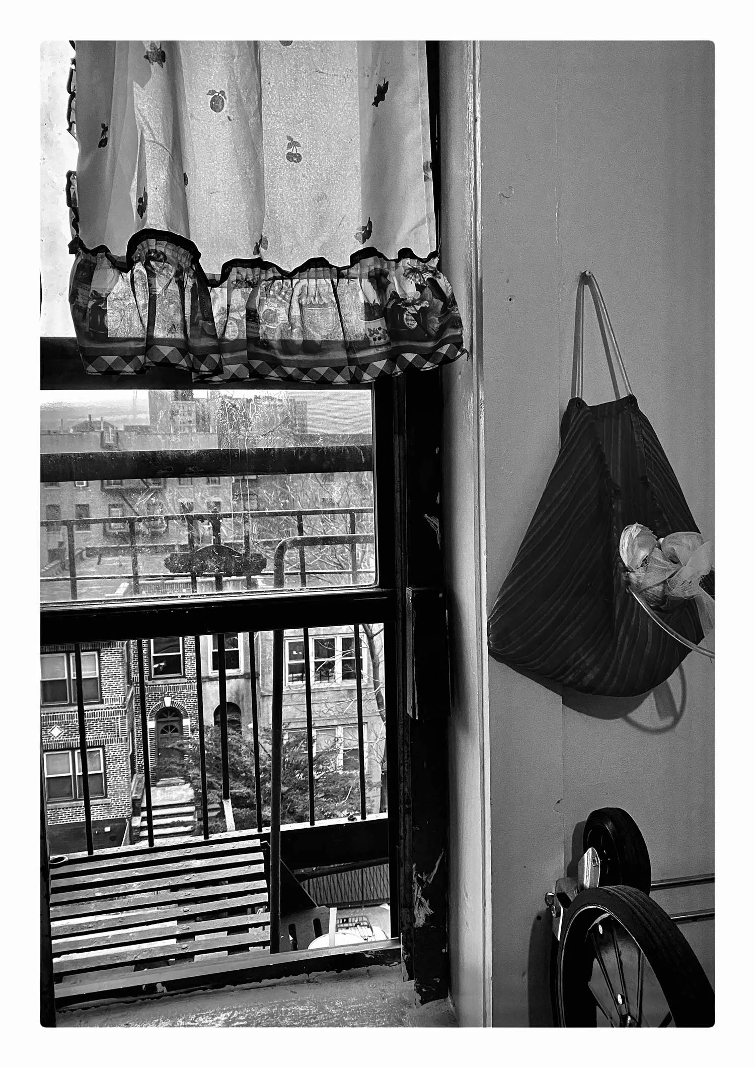 A purse hung up next to an open NYC apartment window. 